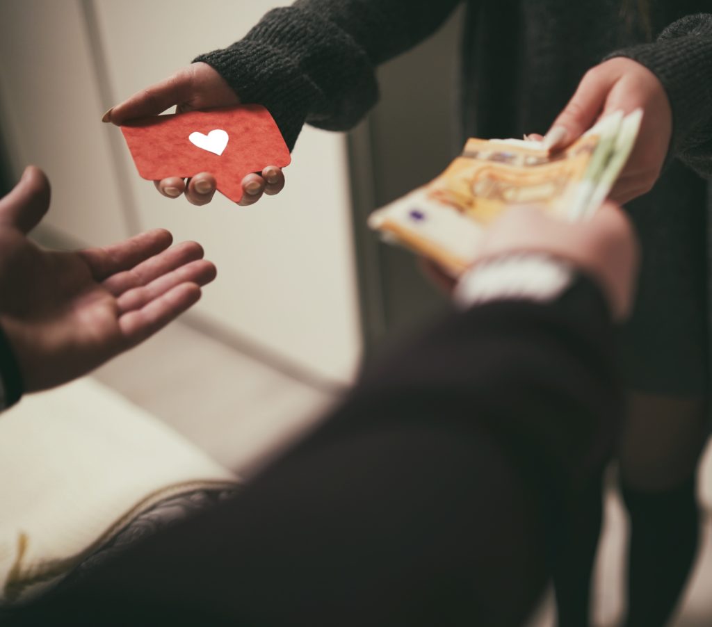 Two people exchanging money for a red card with a heart on it