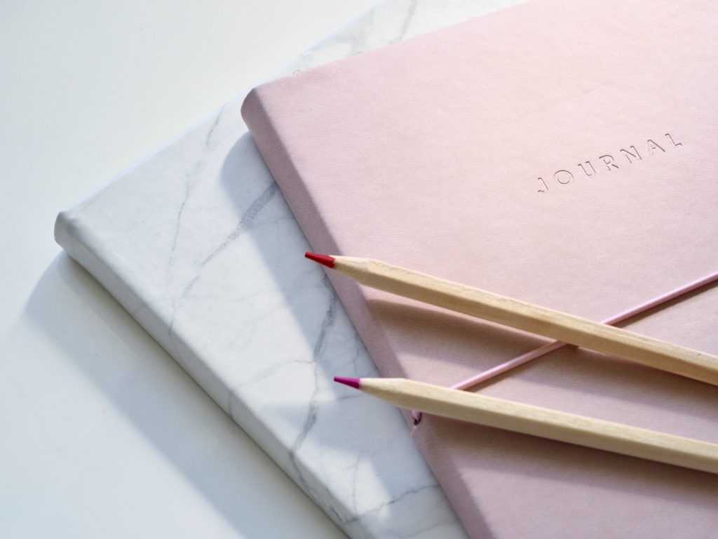 Two journals placed on top of each other, with some pencils on top