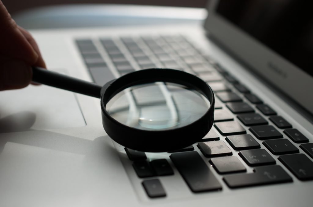 Image of a magnifying glass and laptop for Google Ad Grants post.