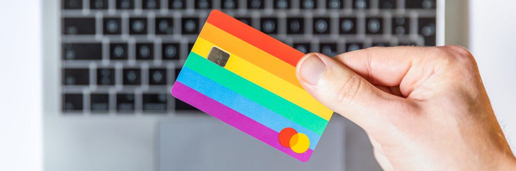 Hand holding credit card above a laptop to illustrate online booking for venue website. 