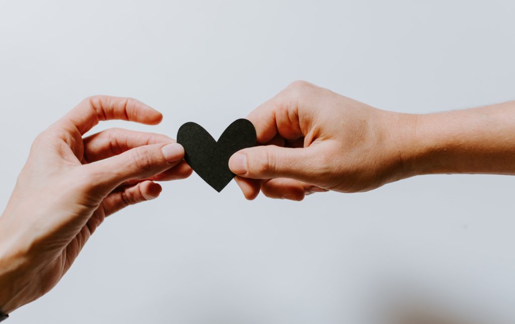 Picture of two hands holding a paper heart.